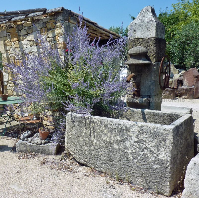 Fontaine murale en pierre vendue avec sa pompe manuelle en fonte ancienne.