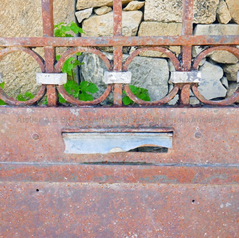 Old gate : an old wrought iron gate animated with forged scrolls and fitted with a mailbox