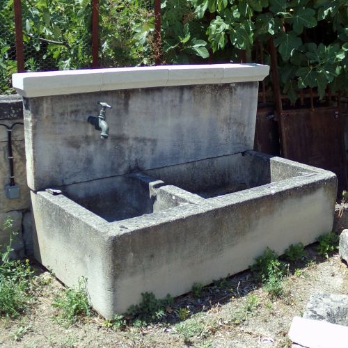 Charming wall fountain with massive basin in stone by Atelier Alain BIDAL in Provence