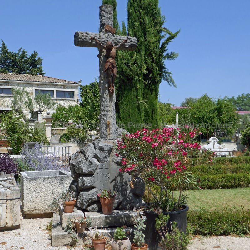 Monument en matériaux anciens: croix en pierre et Christ en fer forgé.