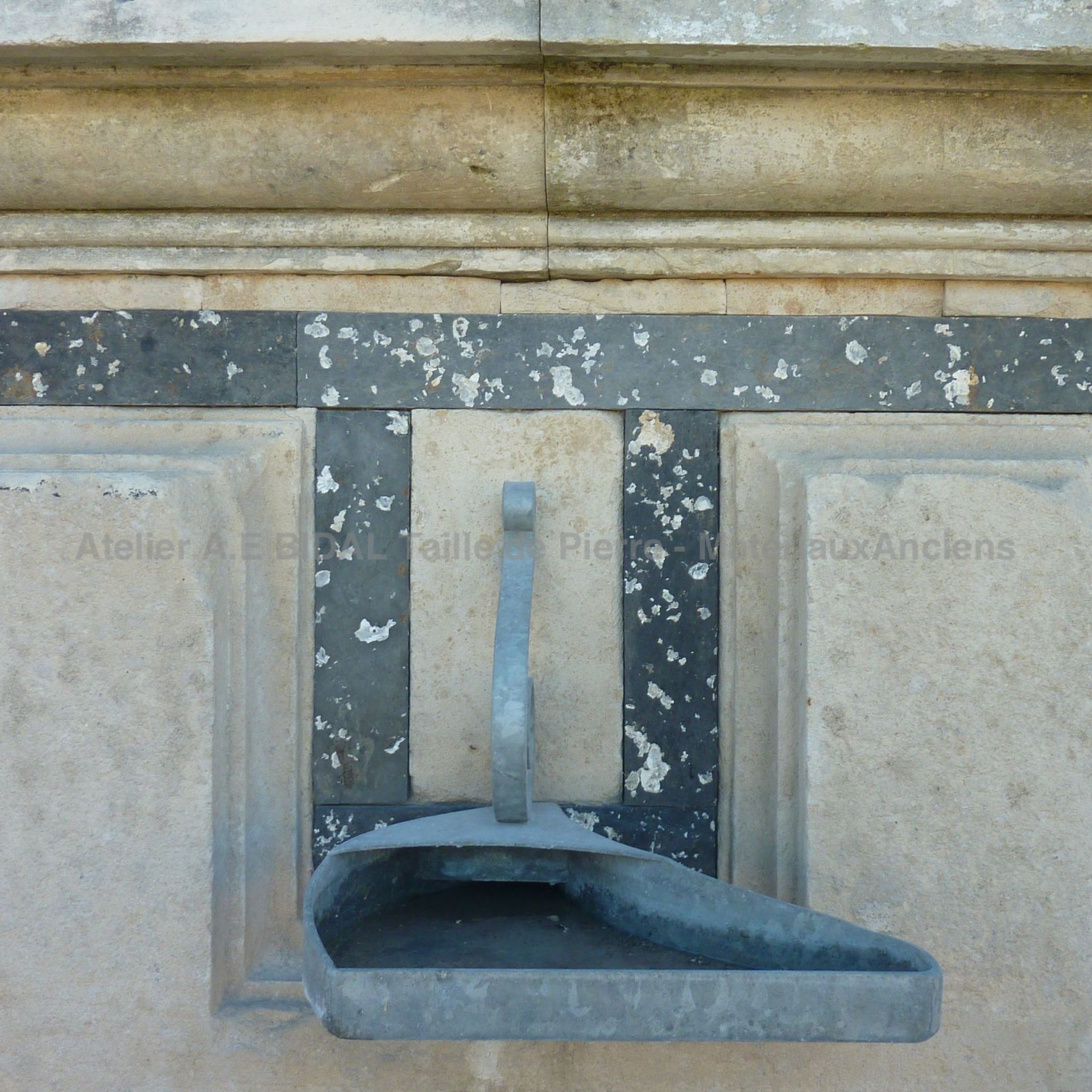 Détail de l'ancienne sortie d'eau en métal sur notre fontaine murale faite de pierres et de métal | En vente en Provence chez BIDAL.