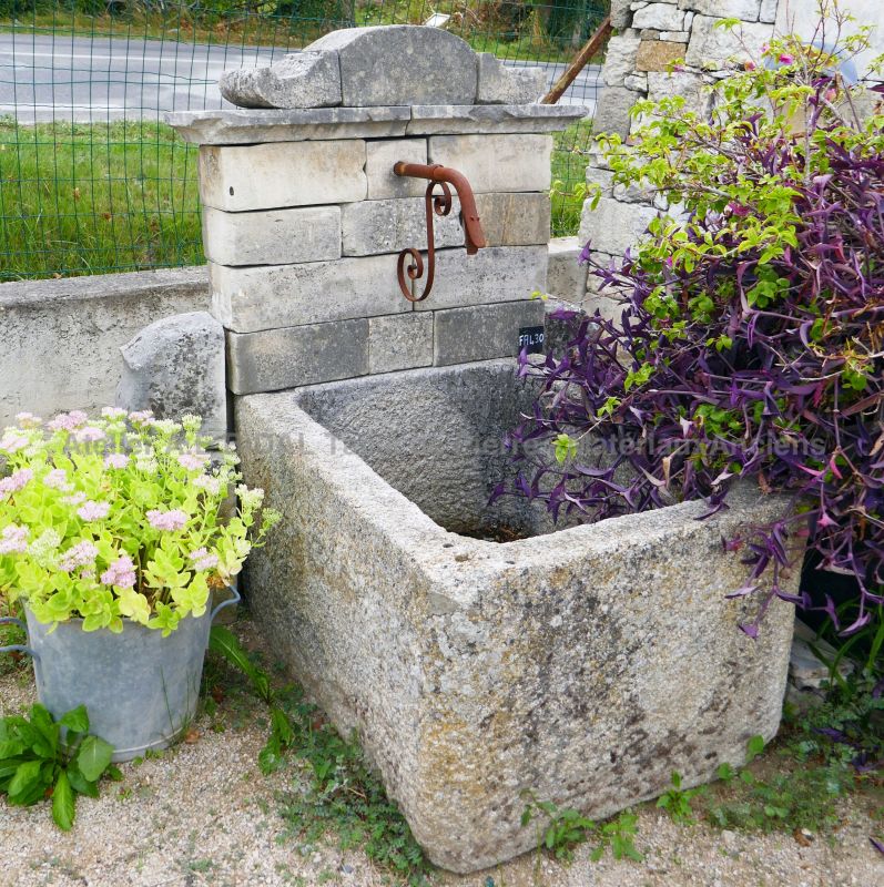 Outdoor fountain with antique trough | Old wall fountain decorated with a stone pediment.