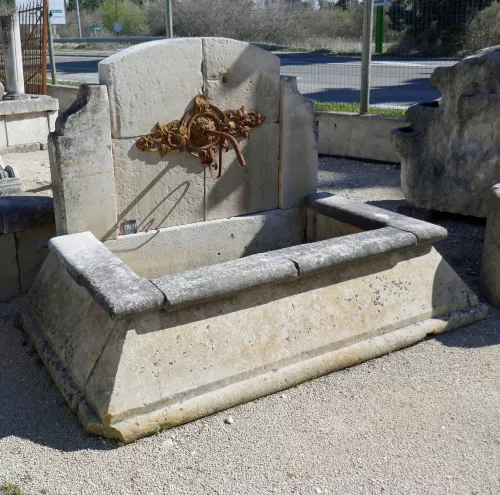 Fontaine en pierres anciennes avec rosace en fonte et bassin évasé