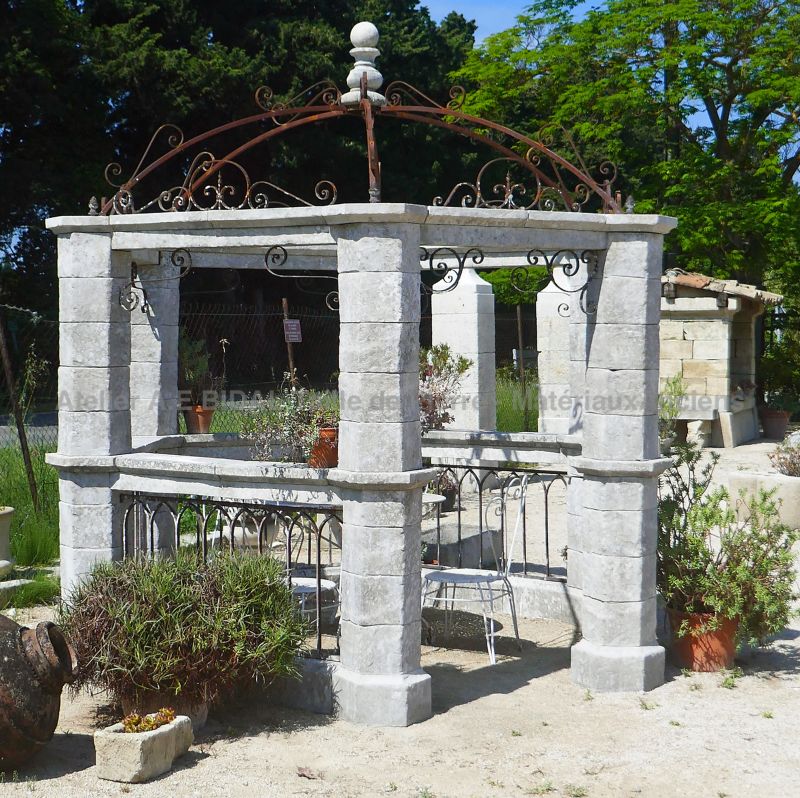 Old-style kiosk with patinated stones and 19th century forged railings.