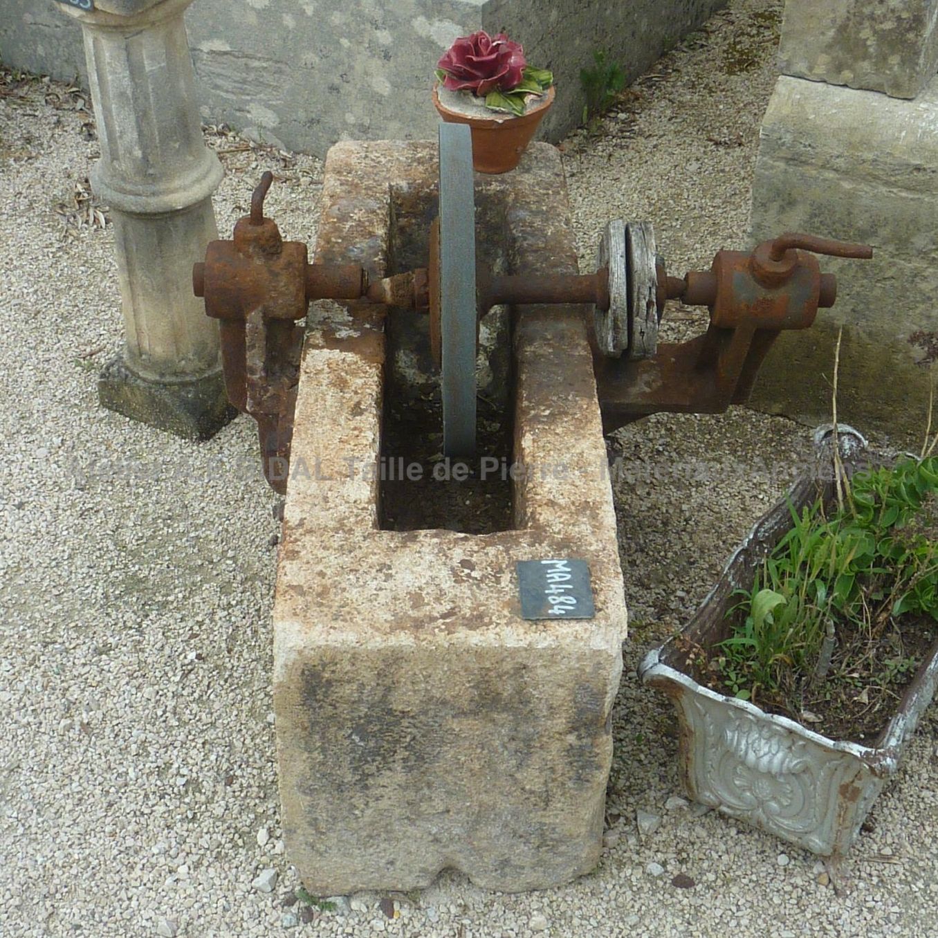 Meule ancienne dans bac ancien en pierre monolithe.