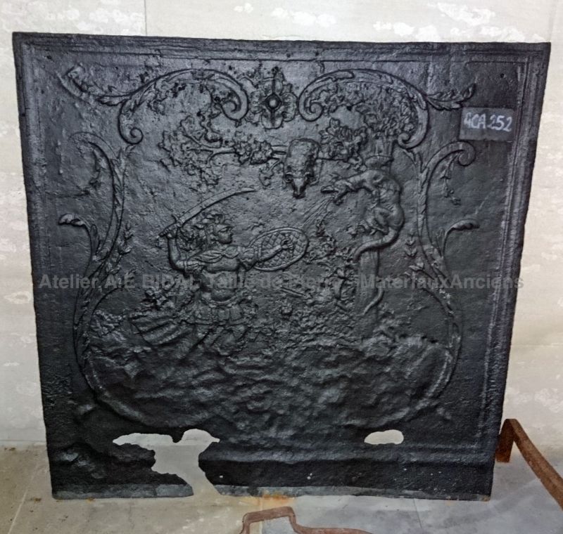 Plaque de cheminée en fonte ancienne représentant une scène d'affrontement dans la mythologie.
