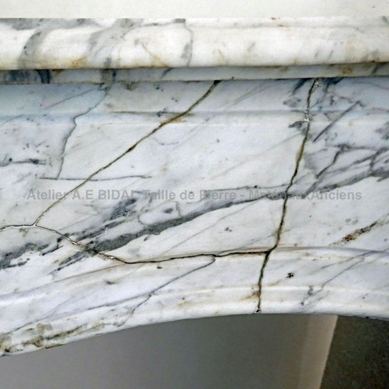 Fireplace in veined white marble in a gray color - beautiful and authentic old fireplace.