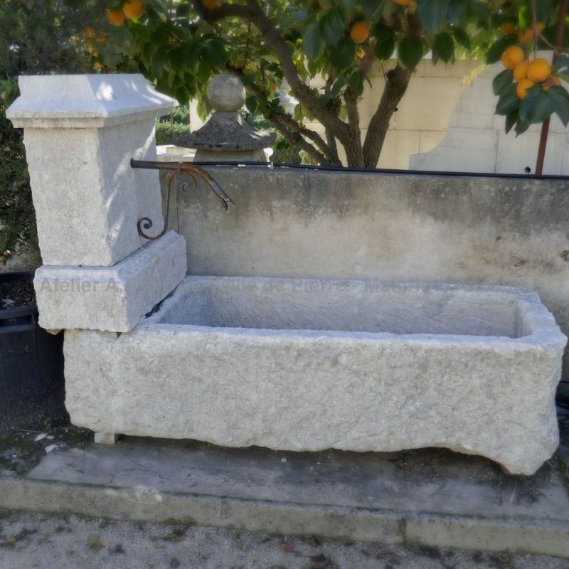 Country-style fountain in white stone for garden landscaping.