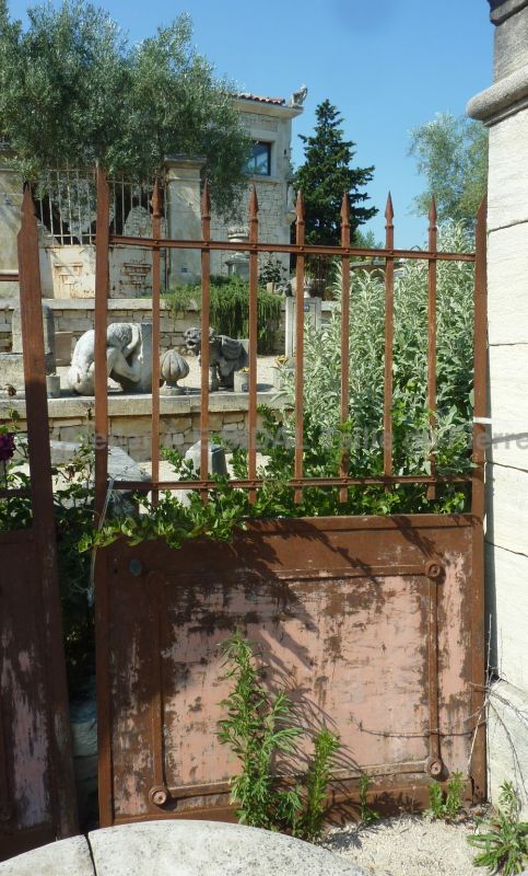 Portail ancien dont le fer forgé à rouillé à sa surface ce qui lui donne beaucoup de personnalité.