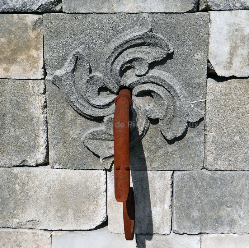 Détail de la sortie d'eau en fer forgé sur le fronton en pierre de notre fontaine de jardin en vieilles pierres | Atelier Alain BIDAL.