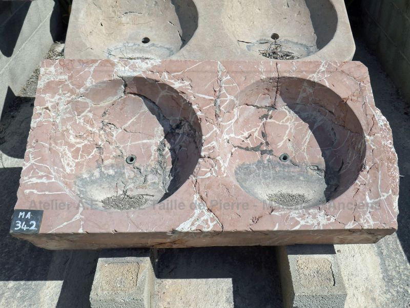 Un évier ancien en pierre rouge veinée de blanc - évier ancien avec vasque double en marbre.