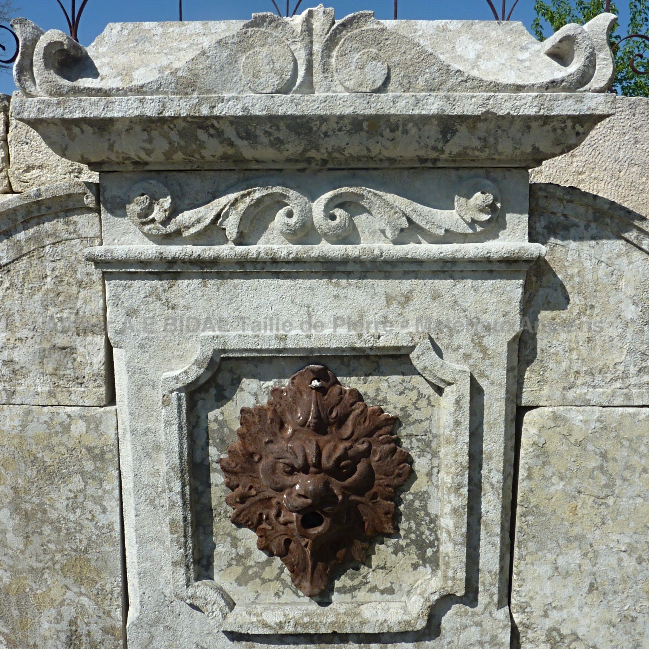 Detail of the cast iron water outlet on our old stone wall fountain | Stone fountain with cast iron lion's head.