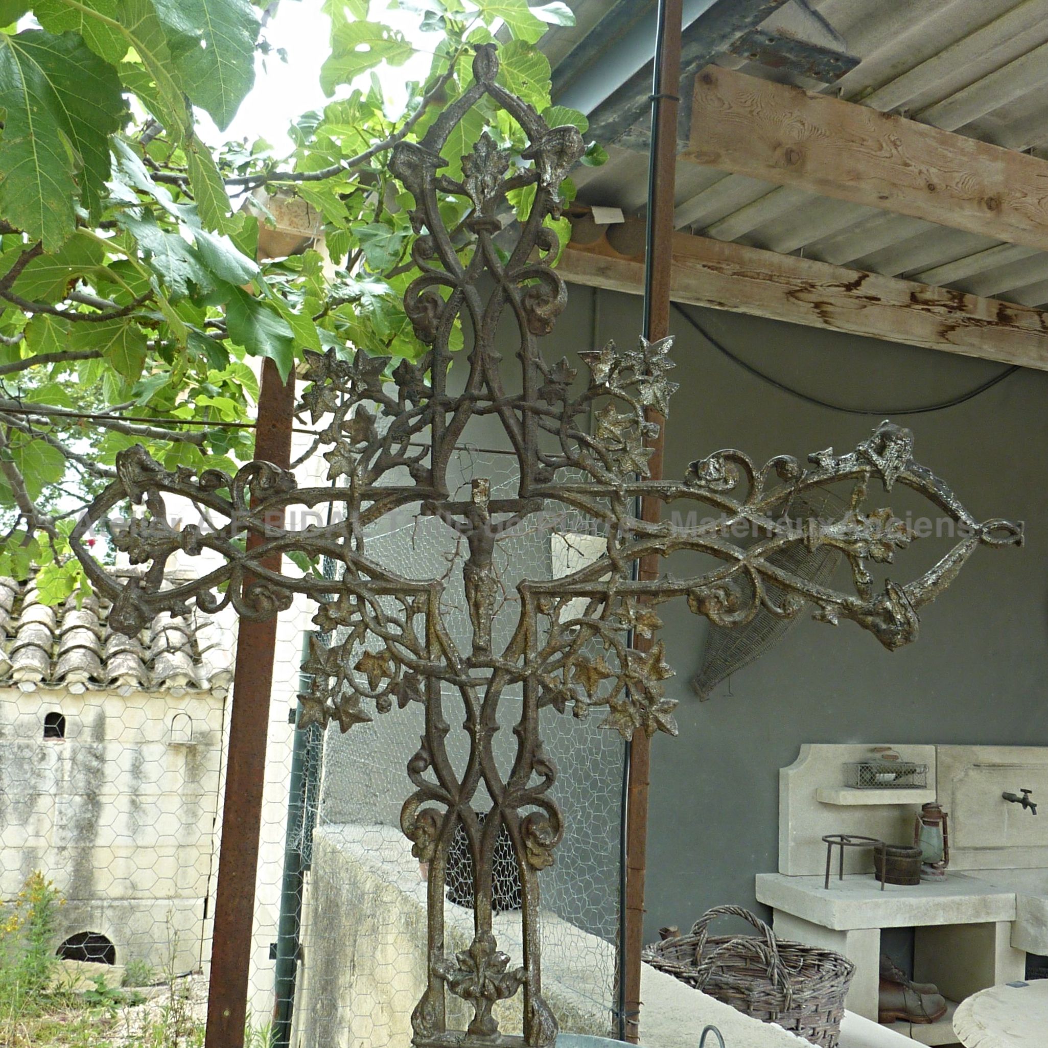 Croix fer forgé avec Christ exposée actuellement dans notre parc d'éléments religieux en matériaux anciens.