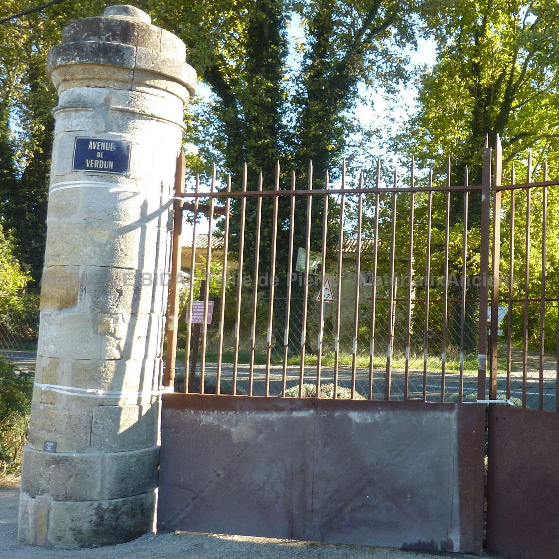 Portail ancien en fer forgé semi-ajouré avec ses gonds de fixation - portail en fer forgé de style rustique.