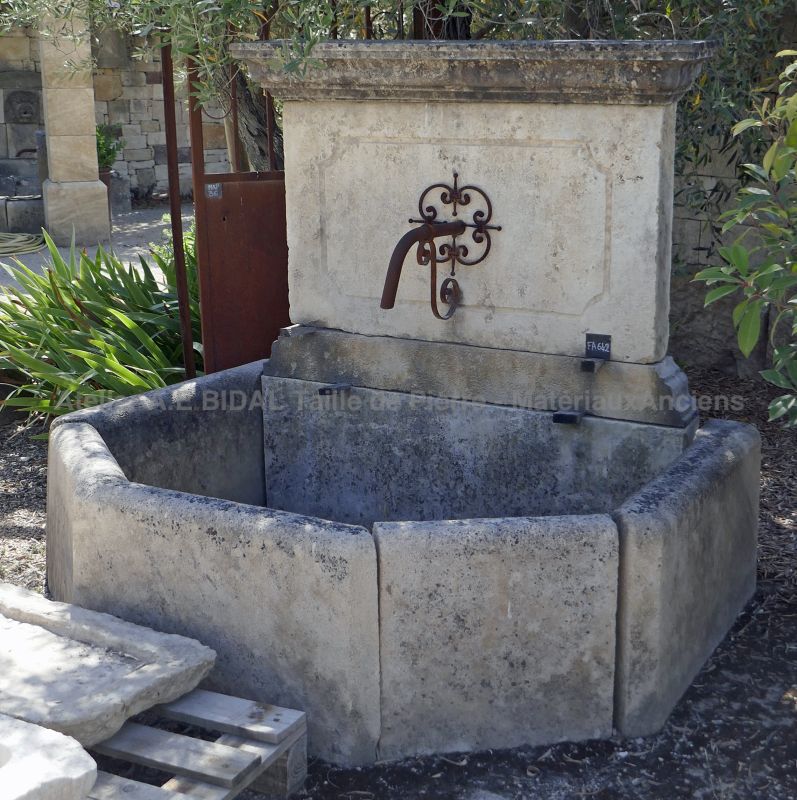 Wall fountain made of old stone with molded pediment: a romantic outdoor fountain with basin!