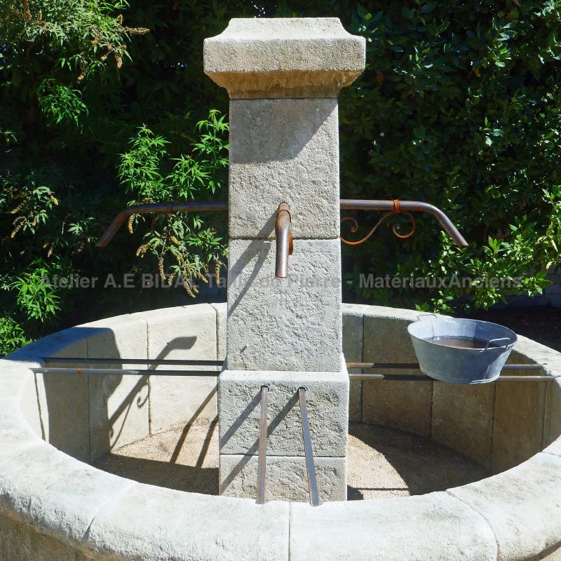 Rustic-looking fountain in weathered stones : round basin and square column - Atelier Alain BIDAL (France)
