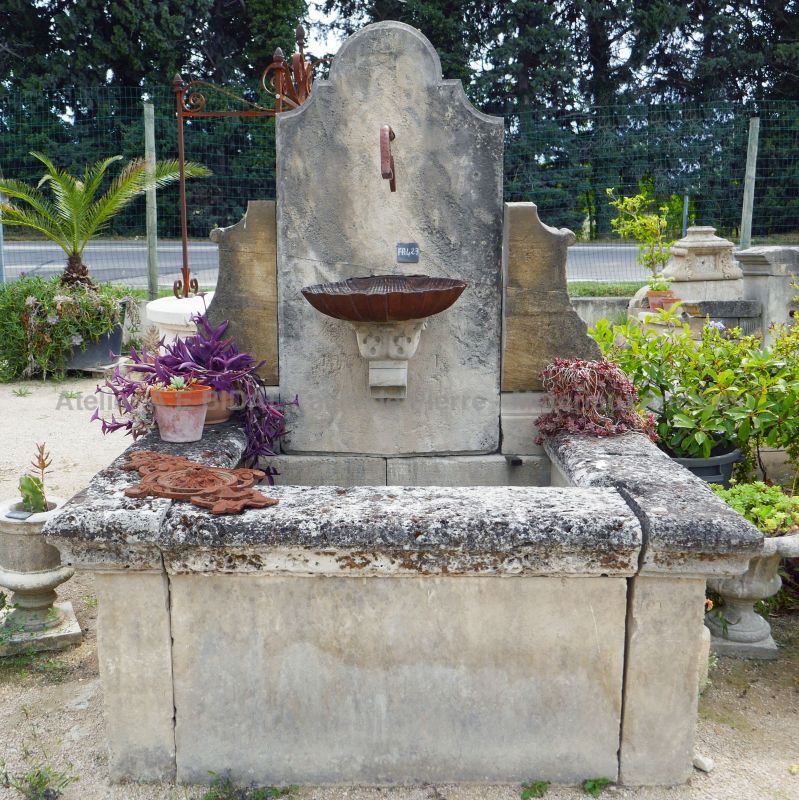 Beautiful wall fountain made of patinated stone and cast iron | Provencal fountain for garden landscaping.